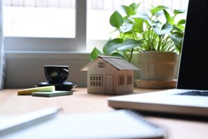 Small house model with laptop on wooden table.